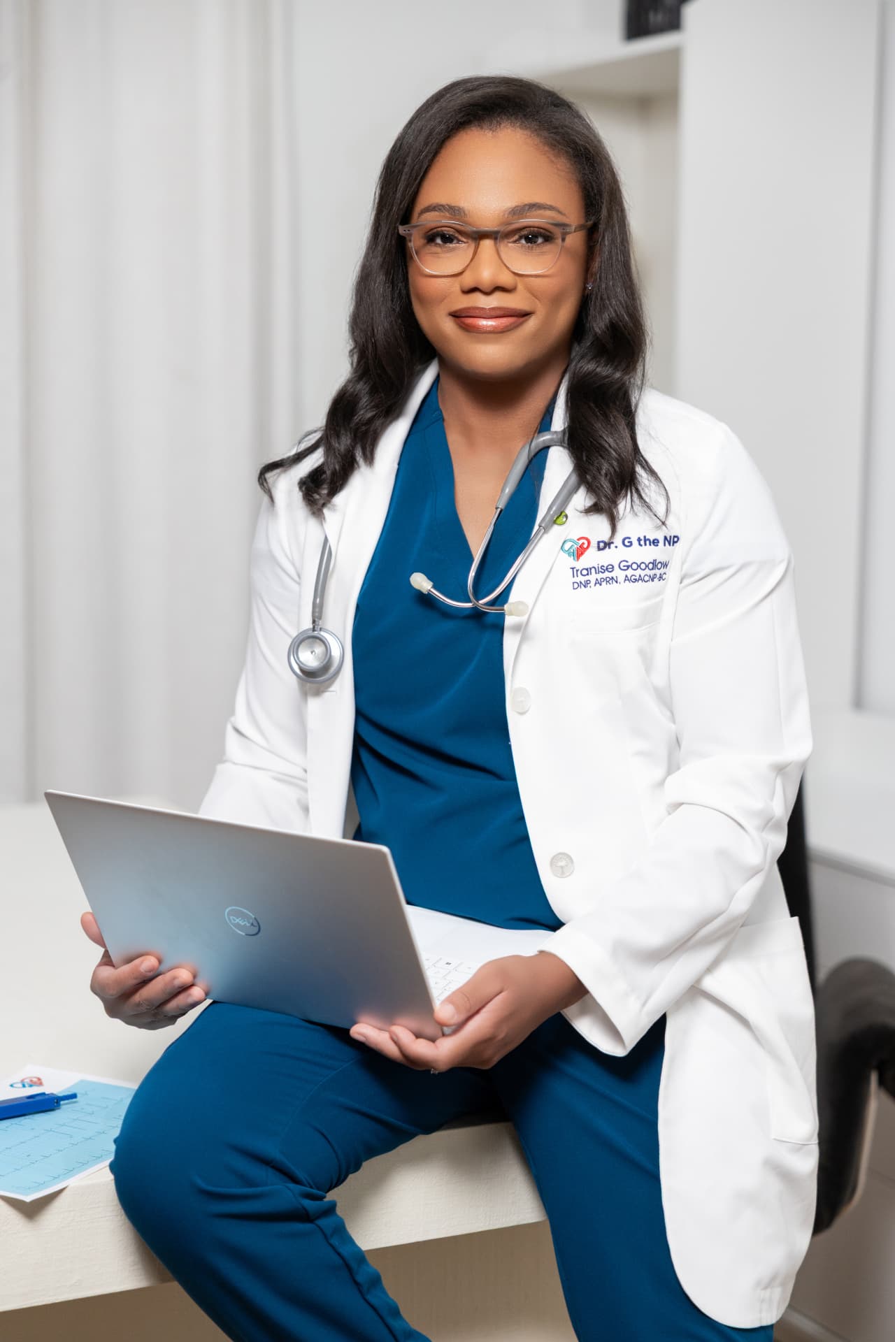 Dr. Tranise Goodlow, DNP, APRN, seated with a laptop and a 12-lead EKG tracing