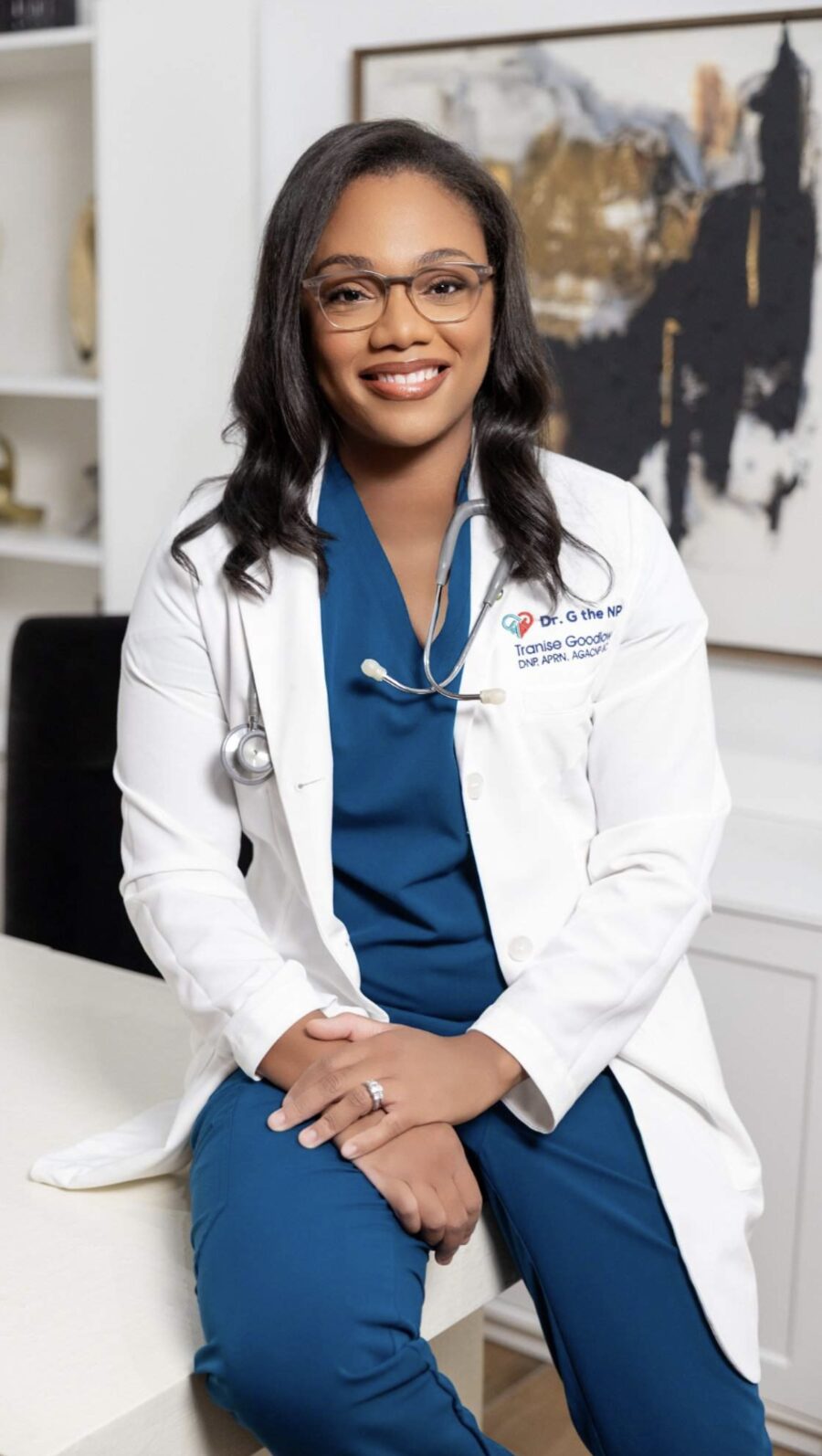 Dr. Tranise Goodlow, DNP, APRN, AGACNP-BC in a white coat and navy scrubs